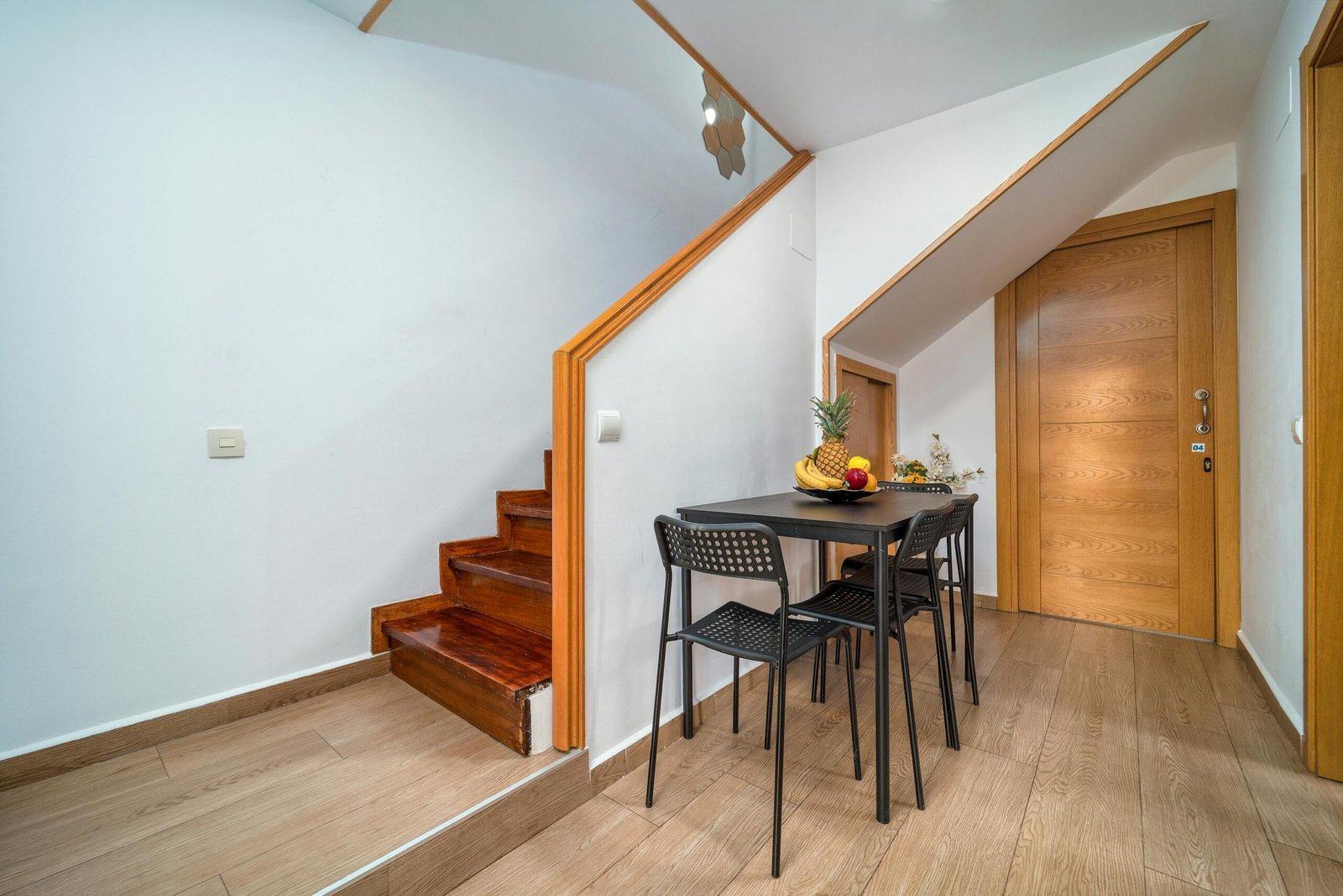 Clean and minimalist interior with wooden accents, featuring a small dining area under the stairs.