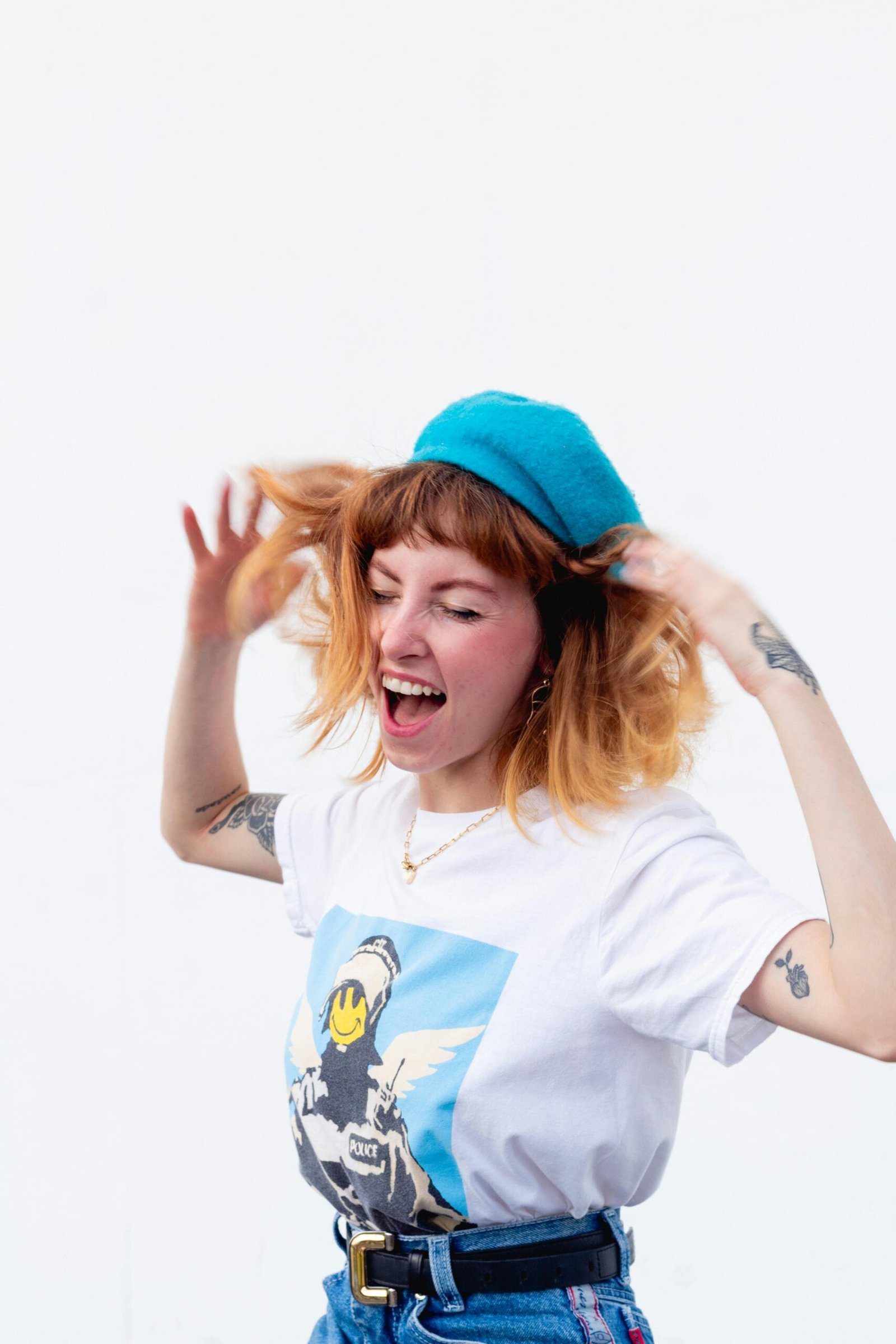 Happy woman with tattoos and vibrant outfit expressing carefree joy with hands raised.