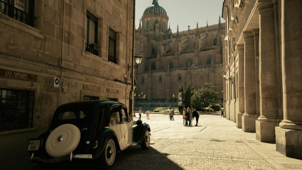 A classic vintage car parked near the majestic Salamanca Cathedral, capturing the essence of historic architecture.